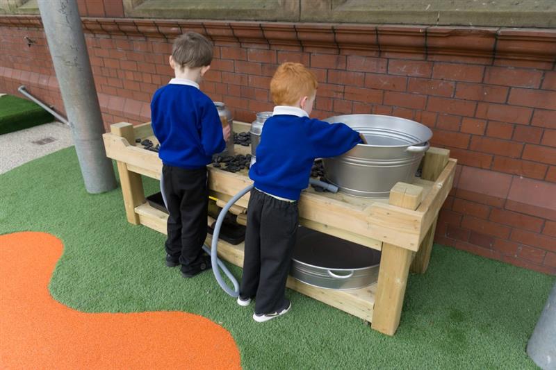 twi children in blue school uniform filling up metal buckets in the timber construction table