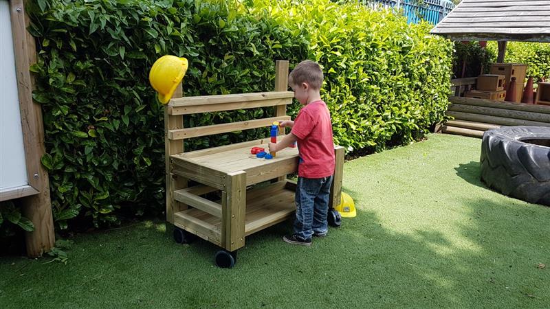 a child plays with the timber construction table on wheels