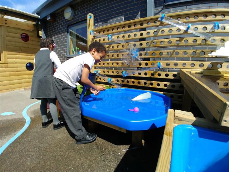 a child plays with the mini tuff spot table underneath the water wall