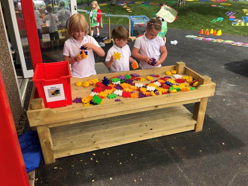 three children playing the blocks on the wooden construction table