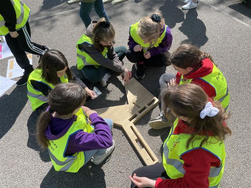 a group of children gatehr around the diy school bench wearing hi vis vests and working out the problems themselves