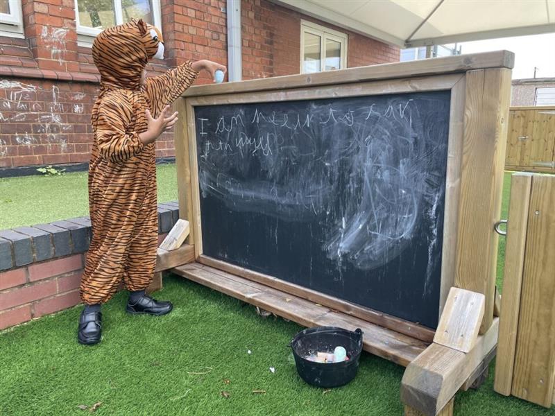 a child in a tiger costume writes on the chalkboard on wheels