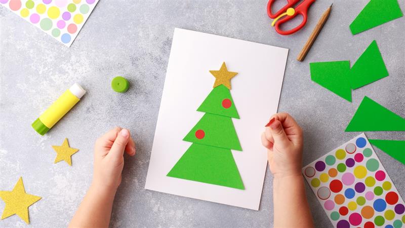 a zoomed in pic of a child making a christmas card with stickers and card