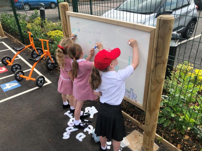 children stand at the whiteboard on posts and write and draw with different coloured pens