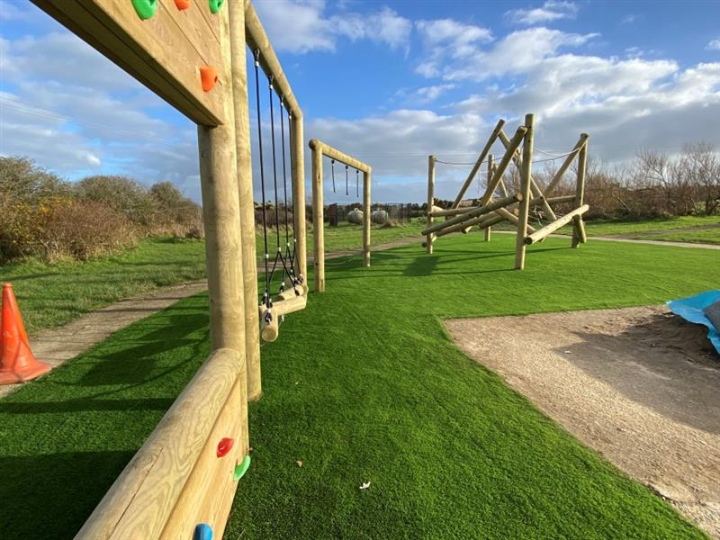 a close up view from the climbing wall all the way across the timber trail n the artificial grass surfacing showing the tryfan climber in the background