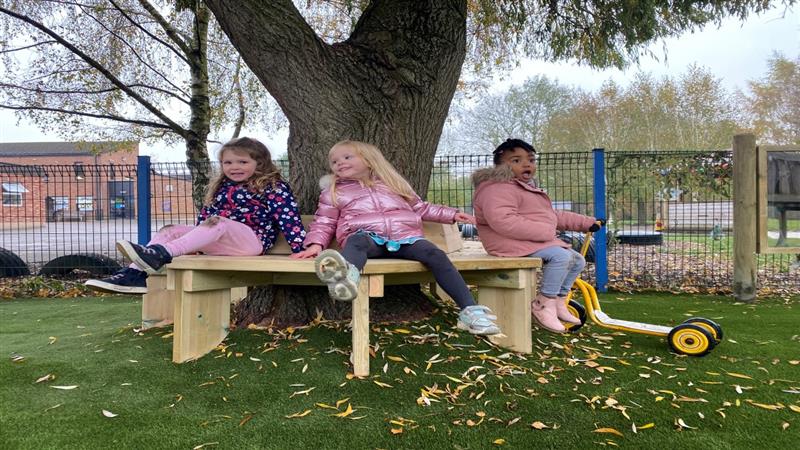 three little girls sit on the octagonal bench