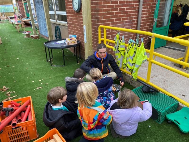 one of our product members sits in an outdoor classroom with some pupils teaching them abut product design