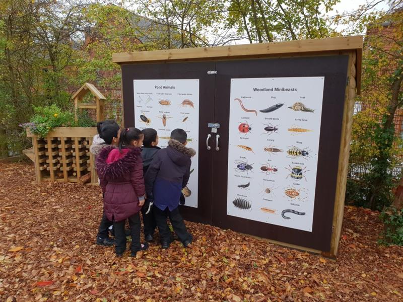 children gather around the front of a self selecting store with a nature identification panel on the front