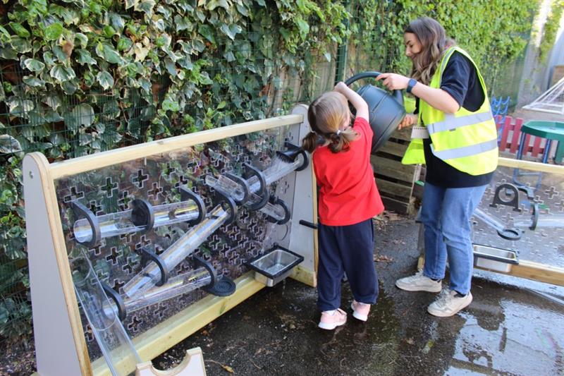 our products team supports a child as they pour a bucket of water down the water channels