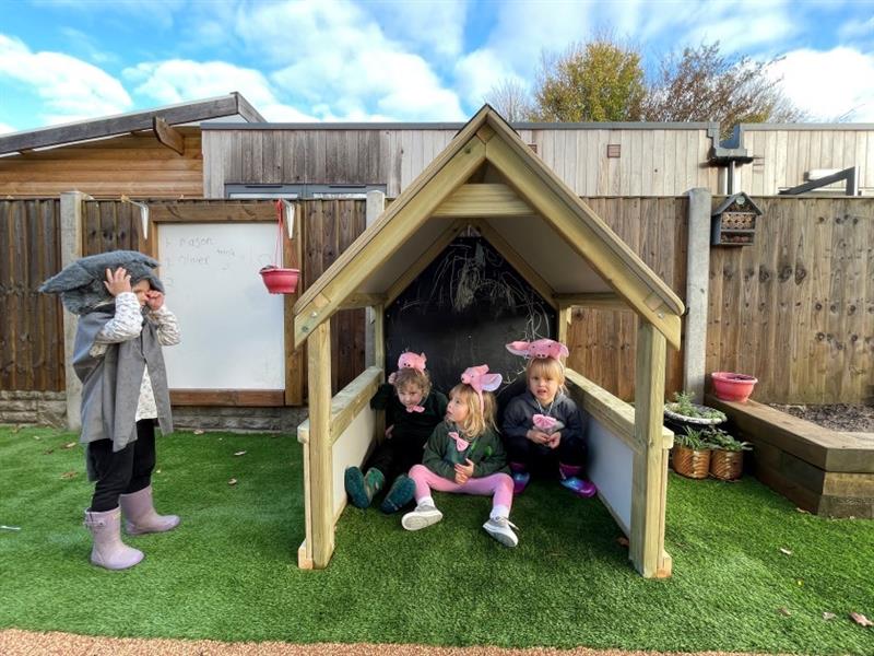 children sit inside the essentials playhouse and pretend to be the three little pigs