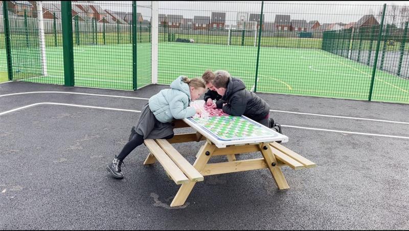 children sit at the gametop picnic table and play games