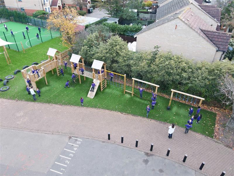 An overhead view of a 20 piece modular play tower installed alongside a hedge row on the school playground