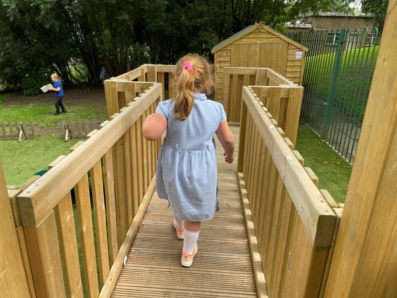 a little girl running across the bridge on the modular play tower