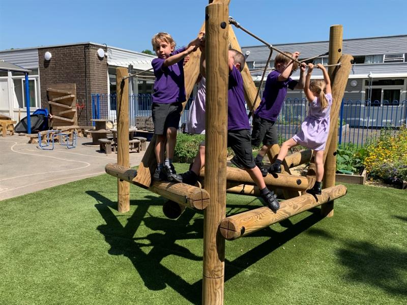 children in purple school uniform climb over the harter fell climber as they hang off the ropes for balance and navigate their way along