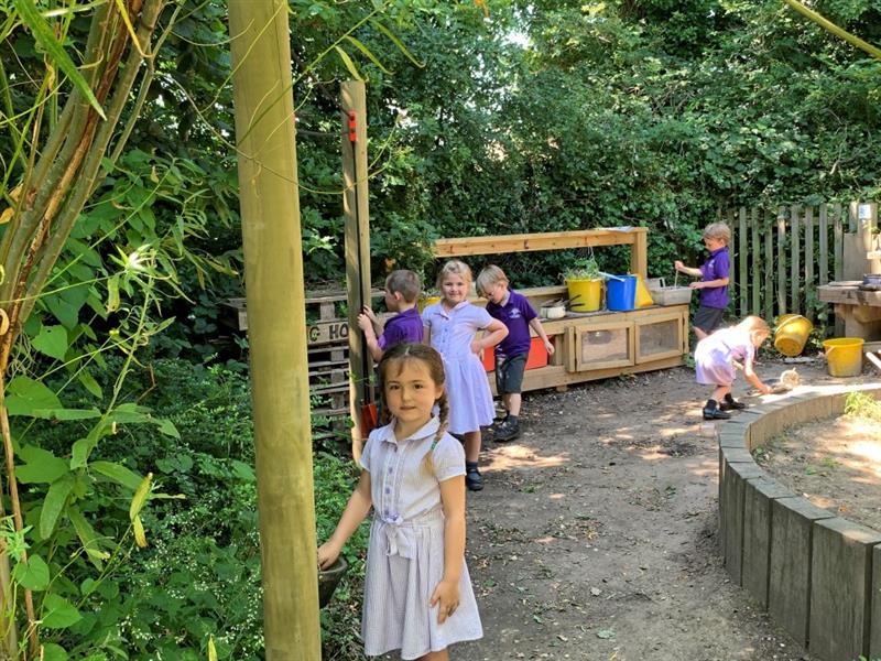 pupils play with both the rope and pulley material movers and the mud kitchen constructed from timber whilst they wear their purple uniforms