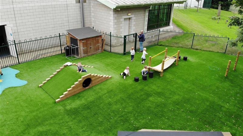 A birds eye view of the eyfs playground at The Riverside Day Nursery, children are playing on the equipment and 2 children are crawling on the floor. 