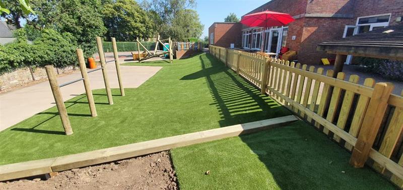 the side view of the timber bow top fencing and the artificial grass 