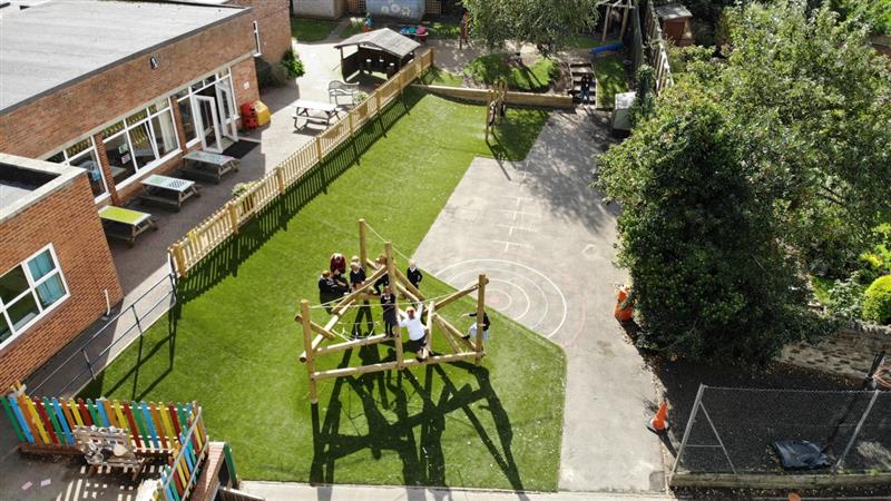 a birdseye view of the completed projct with the bowfell climber, the artificial grass playturf and the bow top timber fencing with the sleeper planter sides