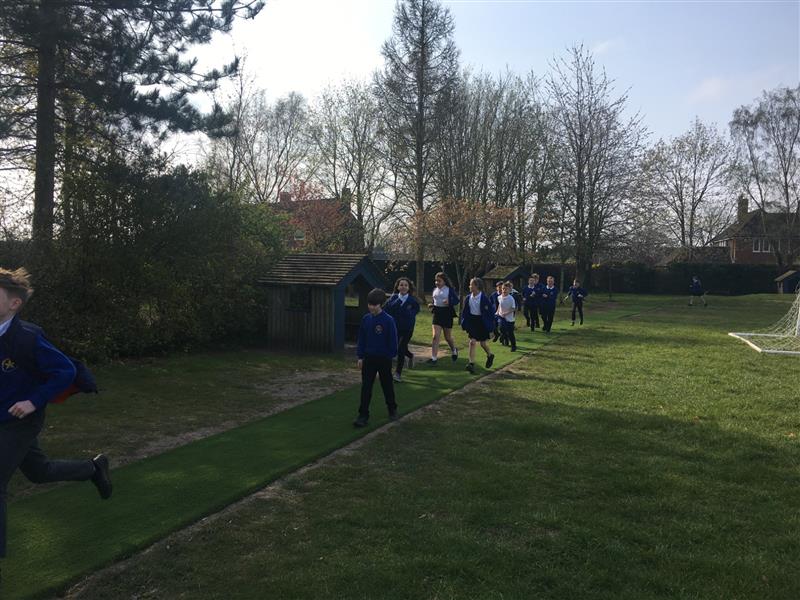 A class of children running along a daily mile track installed onto a school field 
