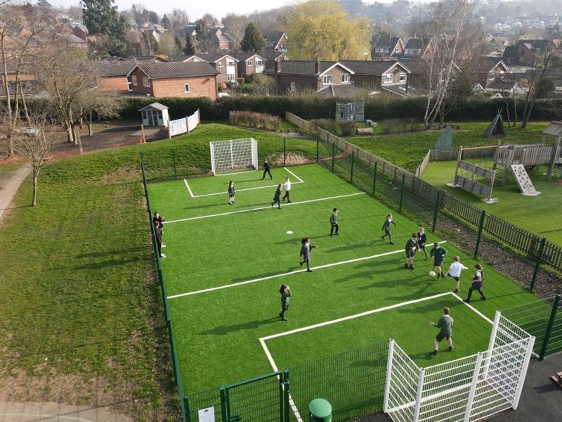 a birdseye view of the muga being played on by children in school uniform