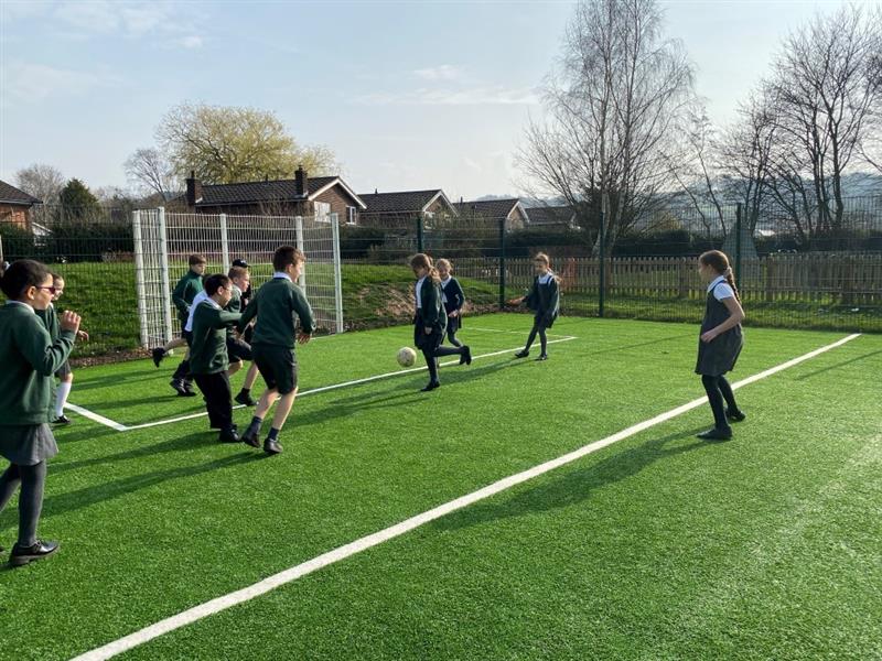children aim for the goal in the muga with a football