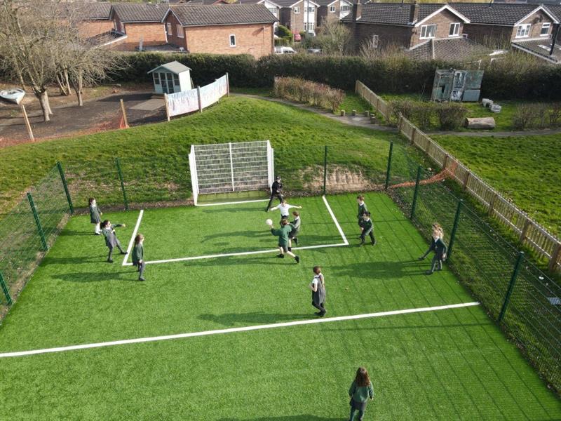 children aim at the goal on the muga pitch