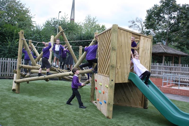 a side view of children in purple school uniform playing on the tryfan climber with a slide and climbing wall