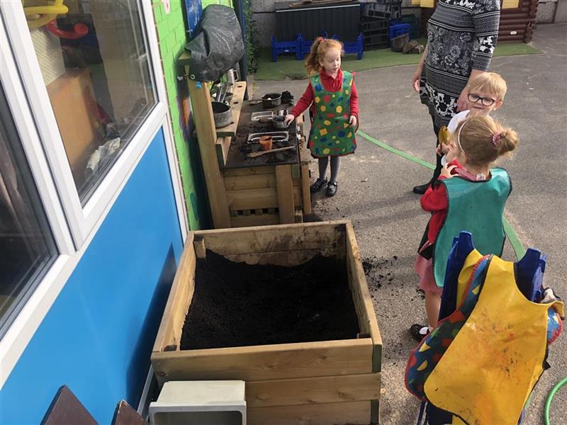 children play with mud kitchens and mud boxes and have messy play time wearing colourful aprons to cover their uniform
