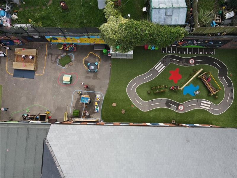 a birdseye view of the foundation playground with green artificial grass playturf and wetpour roadway