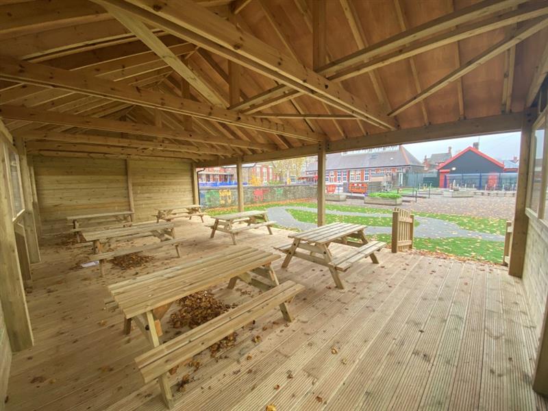The pictures show six timber picnic tables within the outdoor classroom empty and unoccupied