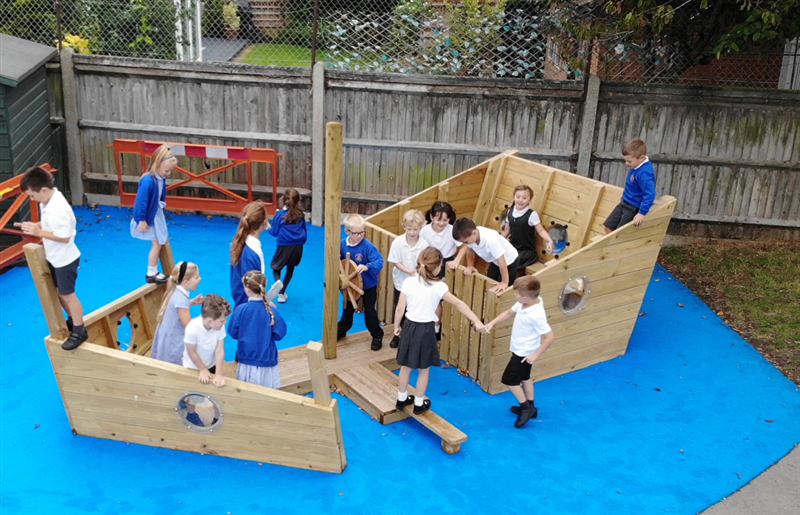 A class of children playing on the play ship, there is blue Saferturf surrounding this area.