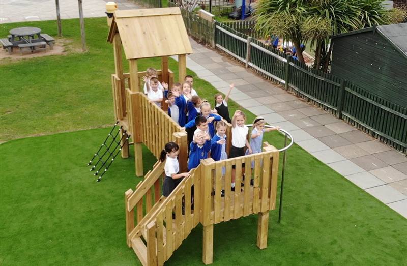children playing on the modular play tower, all the children are waving at the camera.