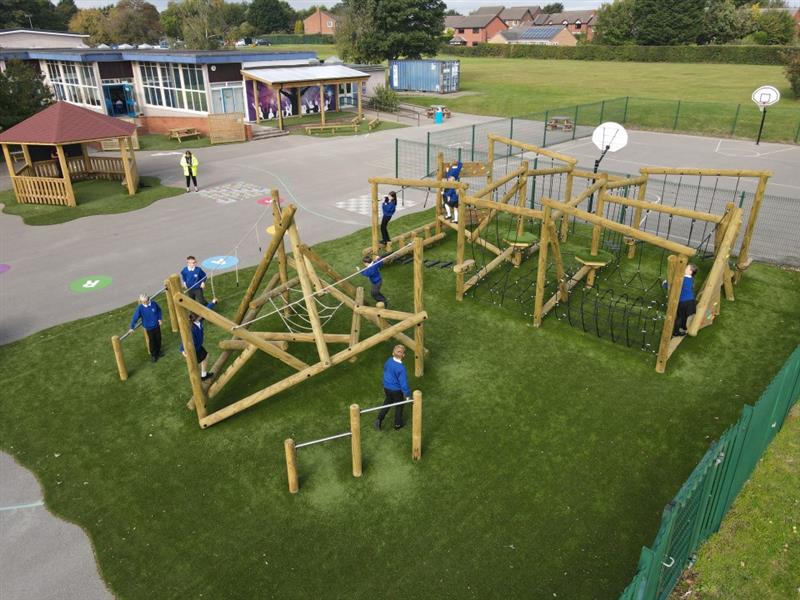 children in blue, white and black school uniform run around on the timber climbing frames and circuits below