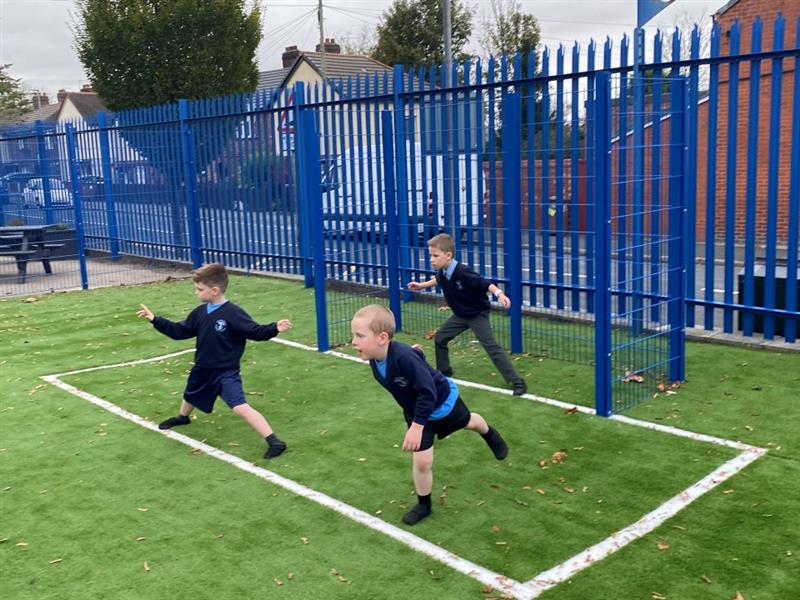 three little boys stand in the goal end of the new muga pitch