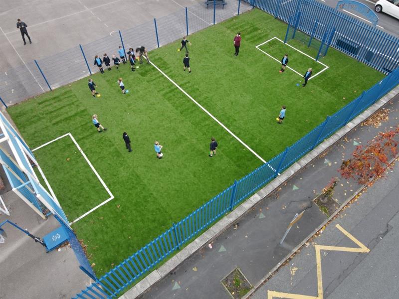 children stand in a semi-circle during  pe lesson on the new muga