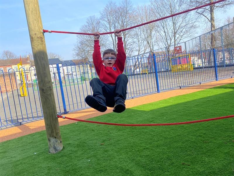 a child swings on the red parallel ropes 