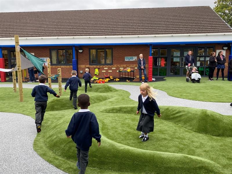 children run on the raised hilltops in the artificial grass climbing up and down as they run around