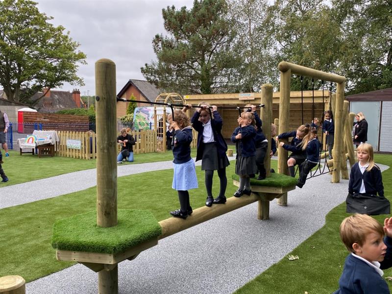 children climb along the rope traverse as a team to help each other out along the wistmans trim trail and then meet on a wooden balance beam connected by artificial grass topped platforms 