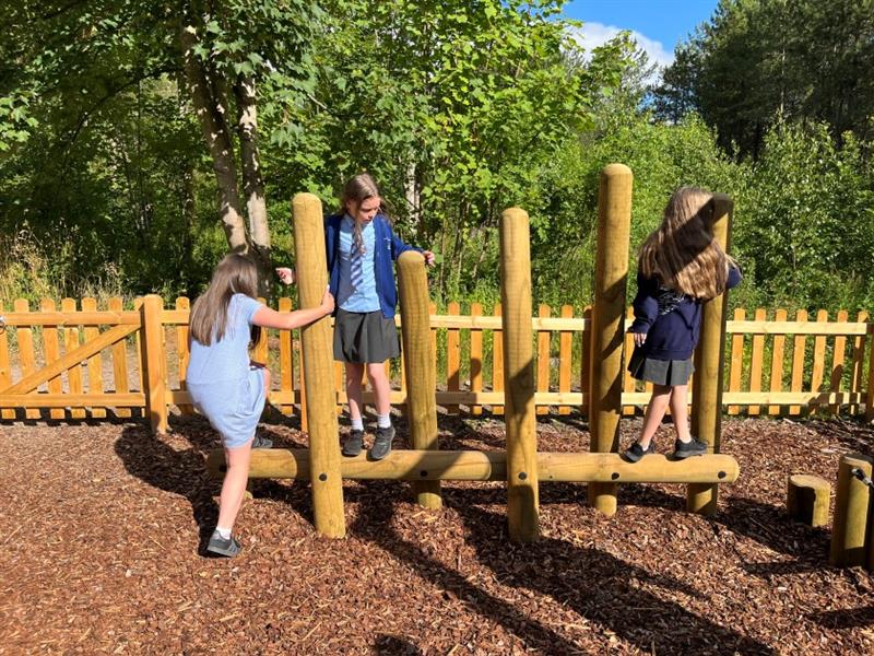 children use the beams to support themselves on the log balance weaver