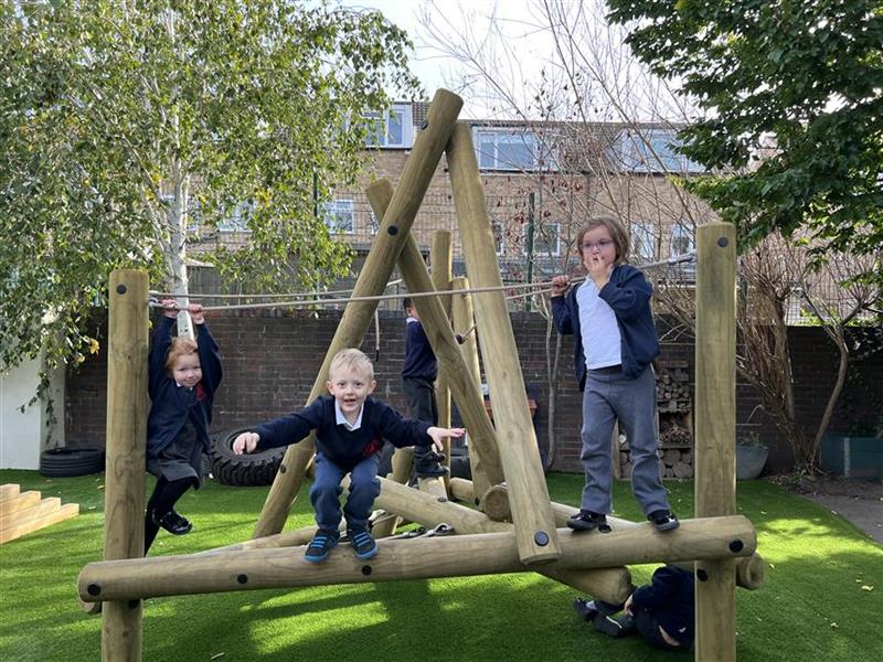 A class of children jumping off the climbing frame in their playground
