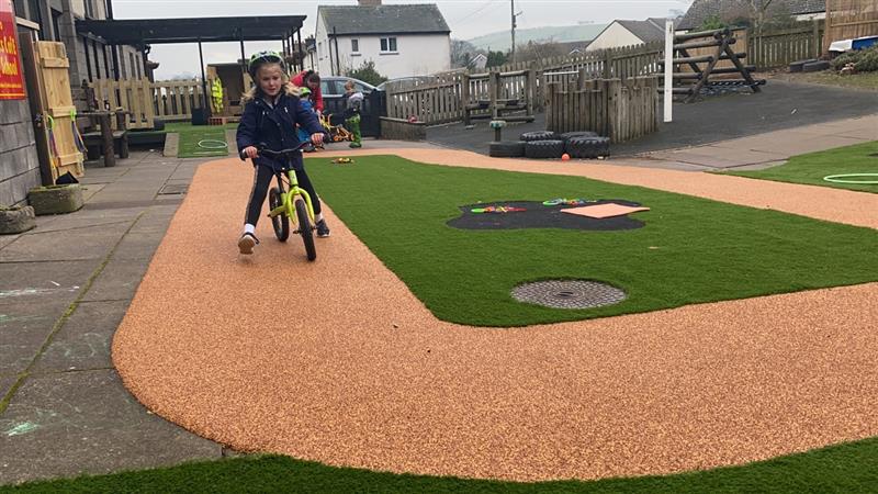a child scoots towards the camera on the beige wetpour surfacing