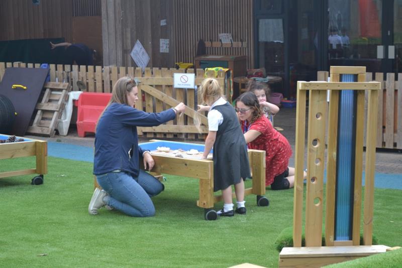 sales consultant, nicole, sits on the floor with a child and a teacher and plays in the messy play table