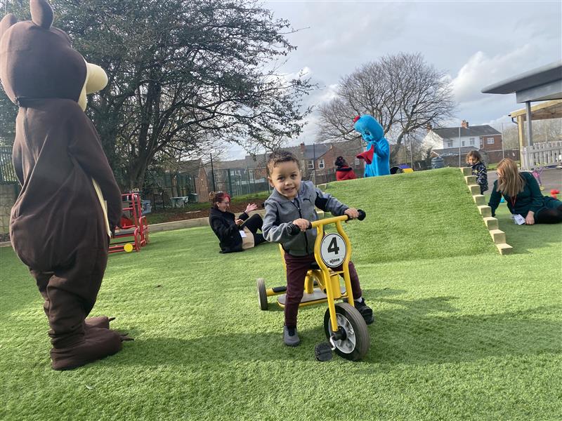 A young boy on a bike whilst riding on the artificial grass