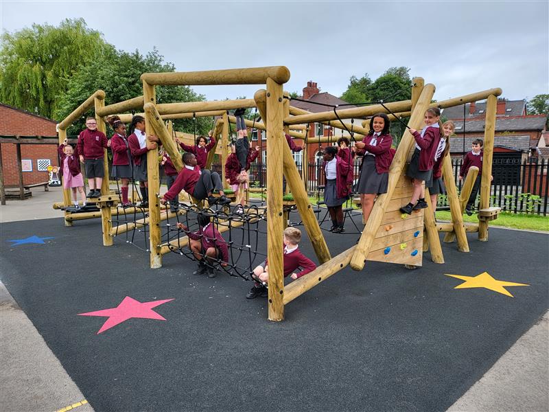 children in burgundy school uniforms climb on the timber climbing frame