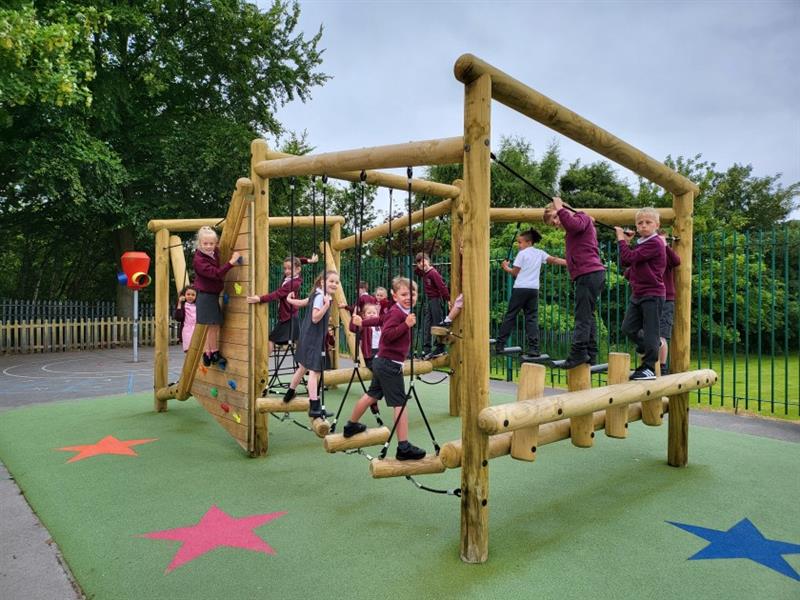 children smile at the camera and climb on the timber climber