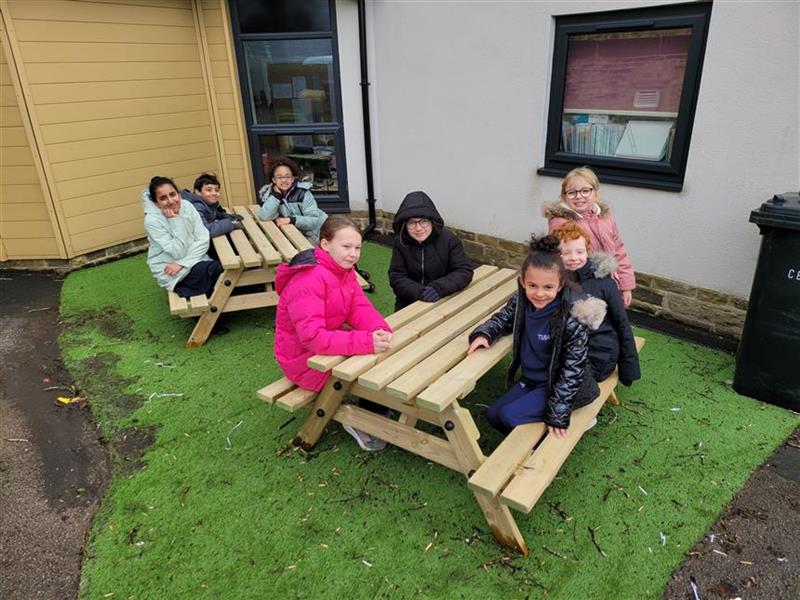 5 children sat on picnic tables at their school.