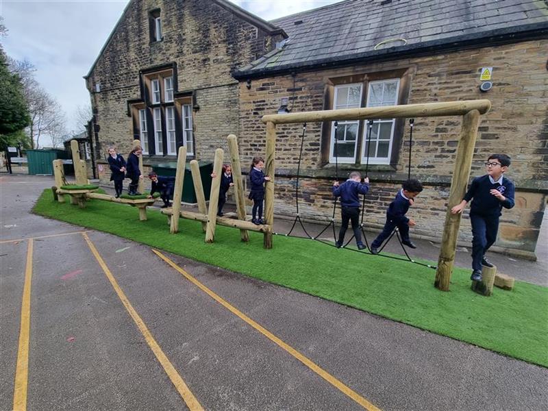 A whole class balancing on the trim trail within their playground at school