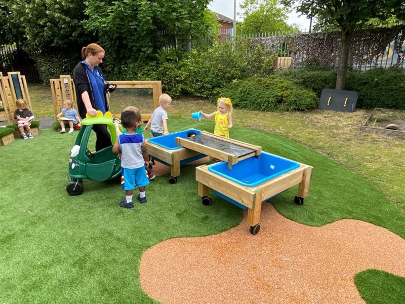 children mill around the water and messy play table