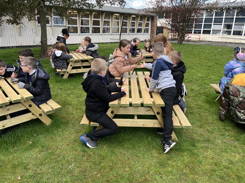 children sit around on the picnic tables and talk to their friends