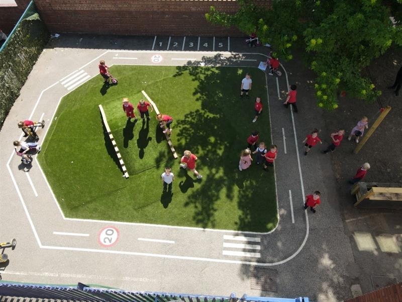 a birdseye view of the grey thermoplastic roadway with children scooting round it